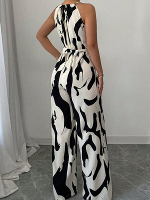 Chic abstract print halter jumpsuit with tie waist and wide legs.