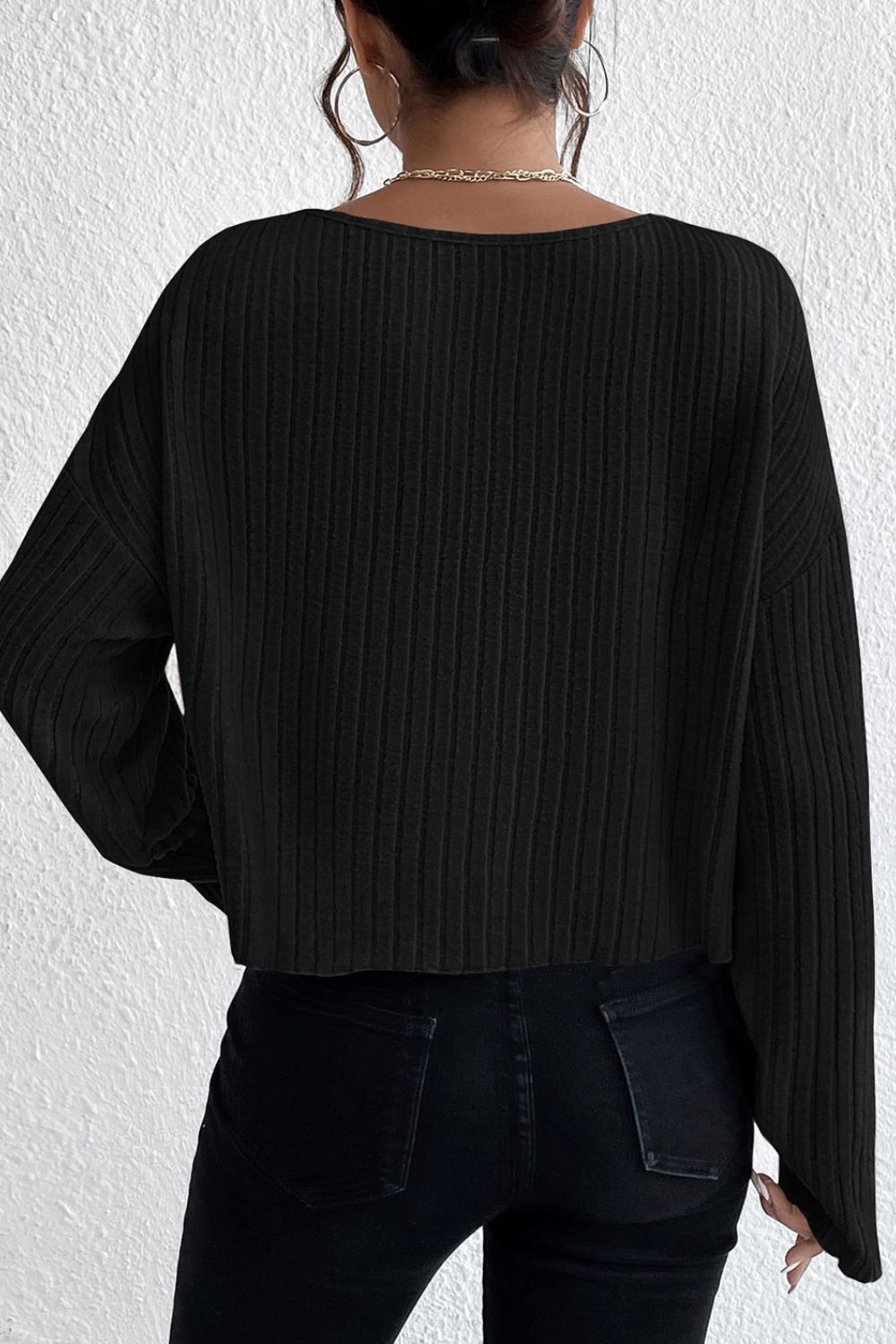 Black ribbed knit off-shoulder top with long sleeves and a cropped hem.