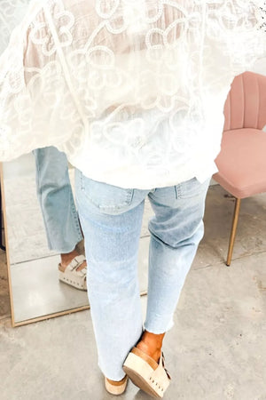 Light wash denim jeans with raw hem and utility pockets, styled with platform sandals.