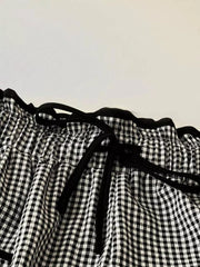 High-waisted wide-leg gingham pants with black tie detail and ruffled waist.