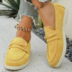 Yellow slip-on loafers with a round toe and decorative strap detail.