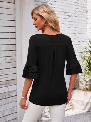 Black blouse with ruffled sleeves and a square neckline.