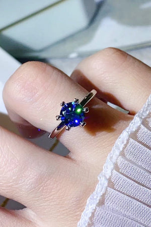 Blue moissanite ring with six-prong setting on a finger