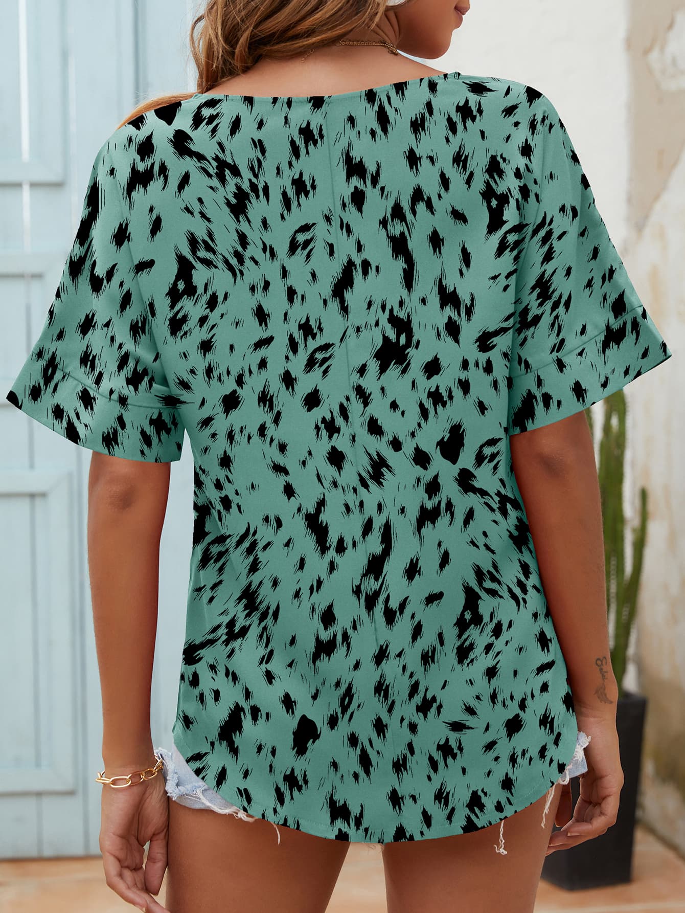Relaxed notch neck top in turquoise with black dalmatian print and short sleeves.