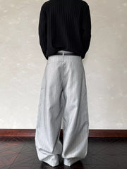 Relaxed wide-leg sweatpants in light gray with subtle vertical pinstripes and a black belt.