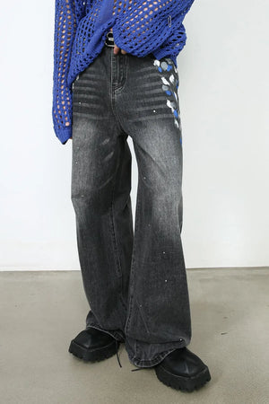 Dark wash flare jeans with artistic paint splatters and abstract blue, white, and gray accents.