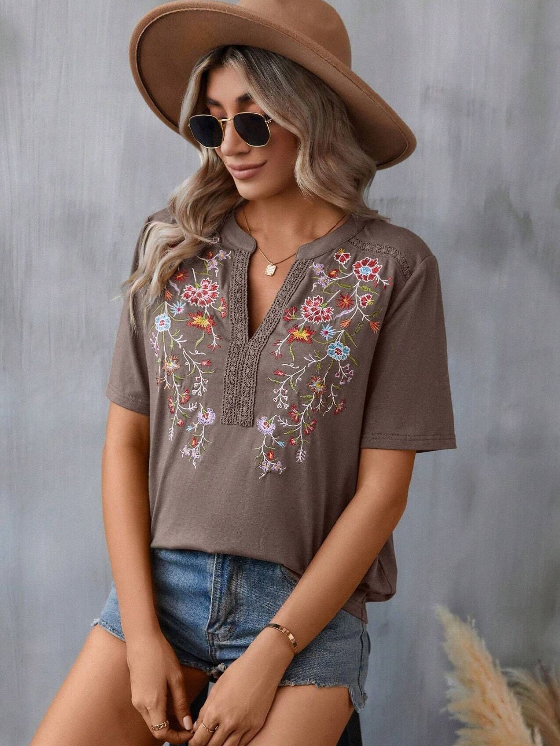 Taupe V-neck tee with colorful floral embroidery and crochet trim detail.