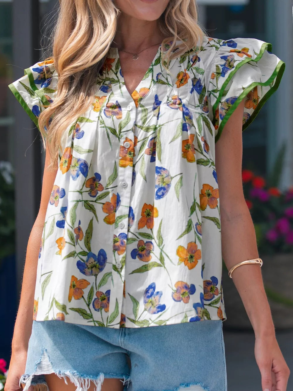 Vibrant floral cotton shirt with V-neck, ruffled sleeves, and button front.