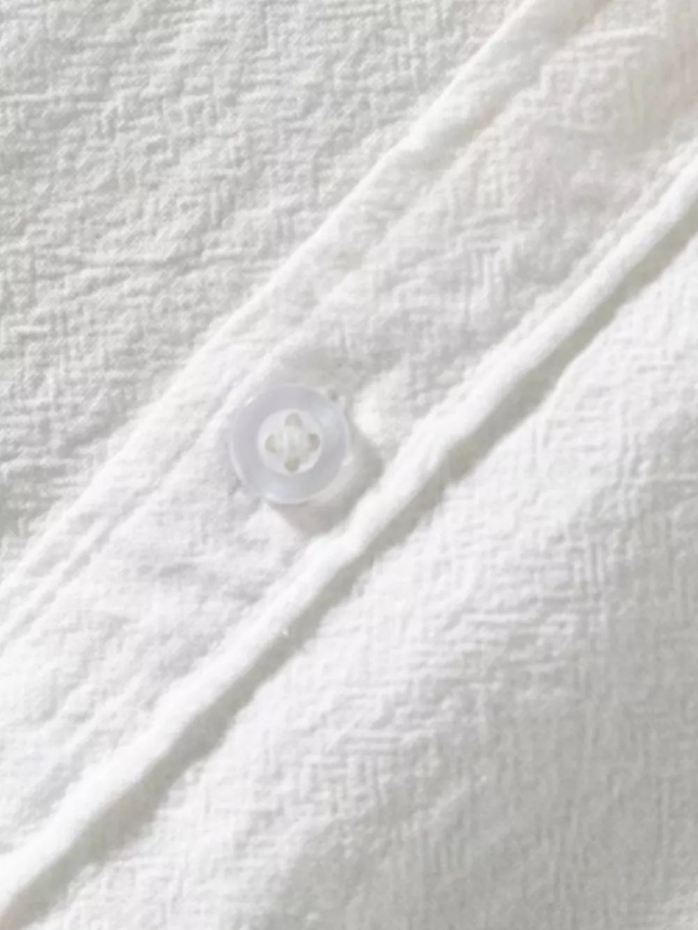 White men's button-up shirt with textured fabric and a single visible button.