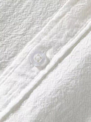 White men's button-up shirt with textured fabric and a single visible button.