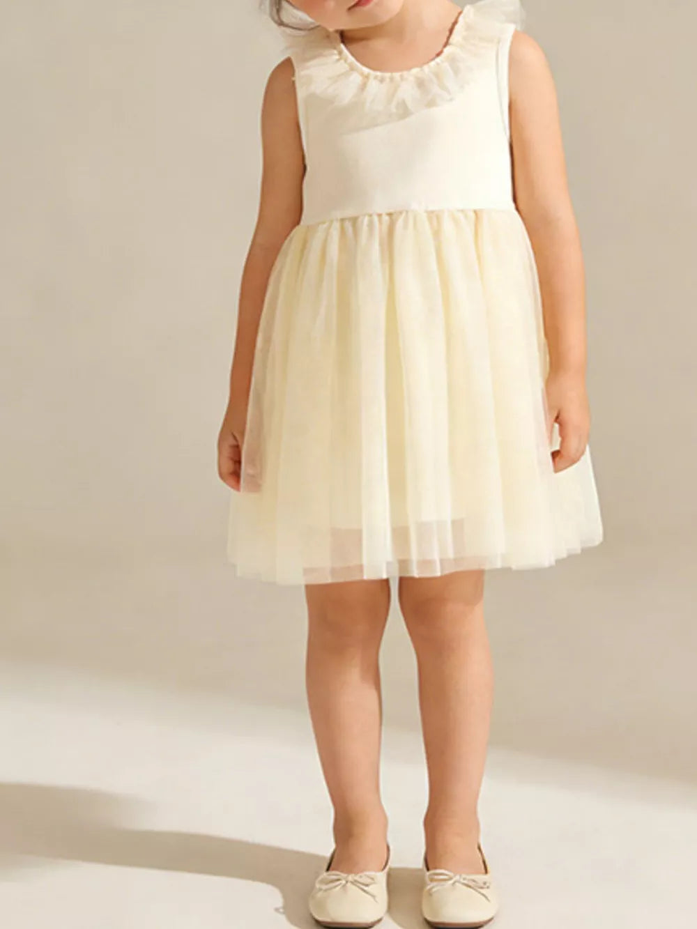 Baby girl's ivory tulle dress with ruffled collar and bow-tie flats.