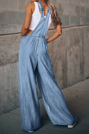 Light wash denim palazzo dungaree jumpsuit with wide legs and adjustable straps.