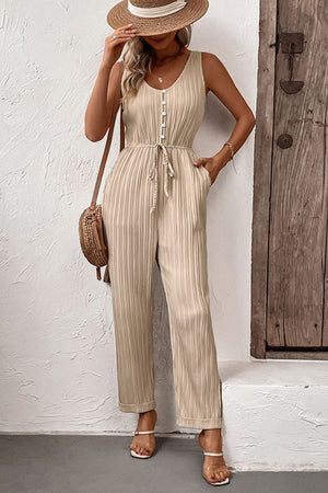 Beige pleated jumpsuit with V-neck, button front, drawstring waist, and wide legs.
