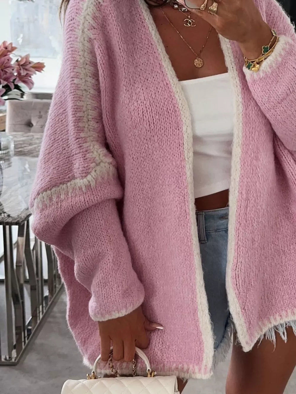 Oversized pink knit cardigan with white contrast trim and textured sleeves.