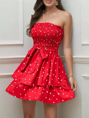 Red smocked strapless mini dress with white hearts, tiered skirt, and bow belt.