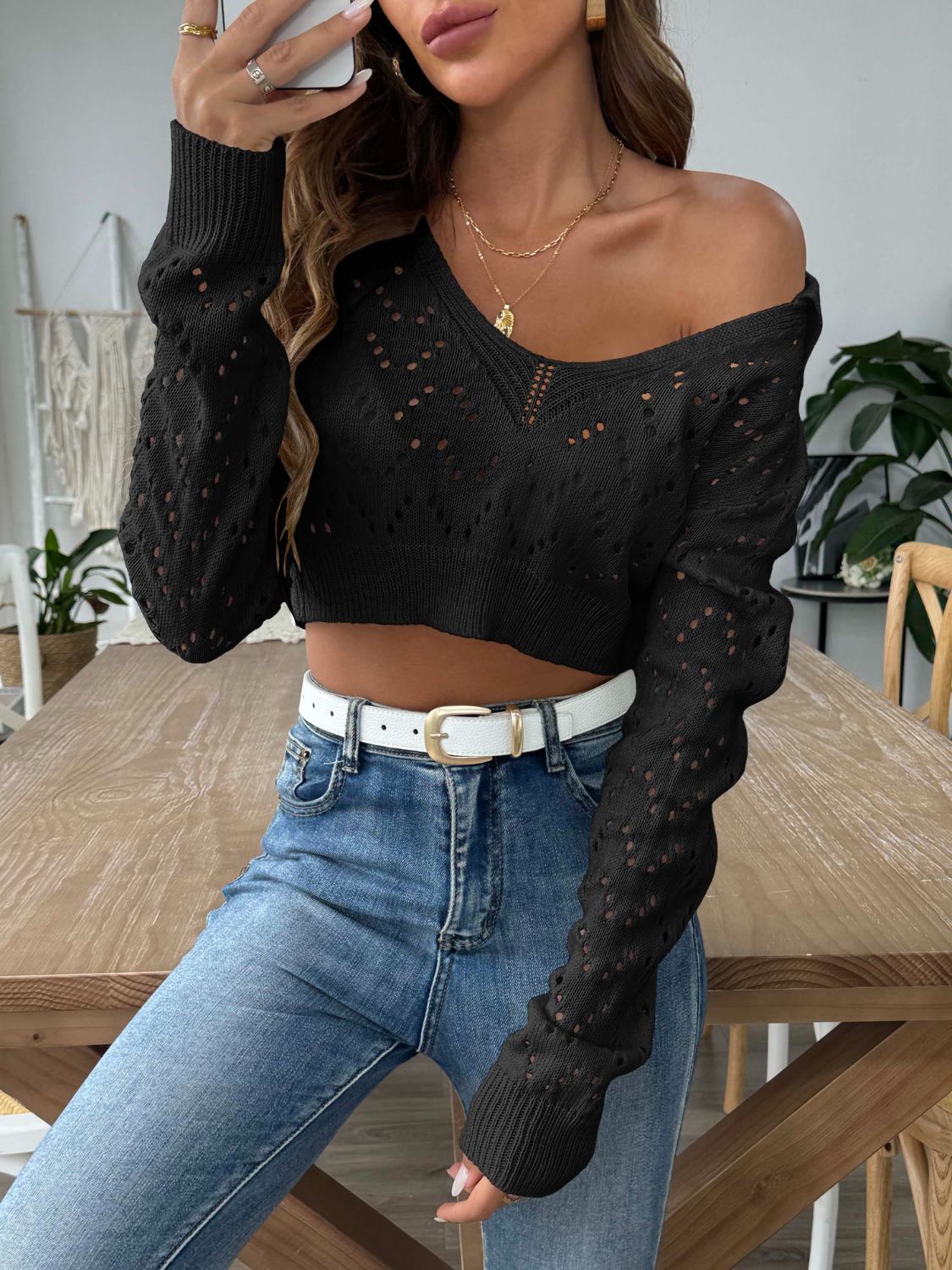 Black cropped pointelle knit polo top with V-neck and long sleeves.