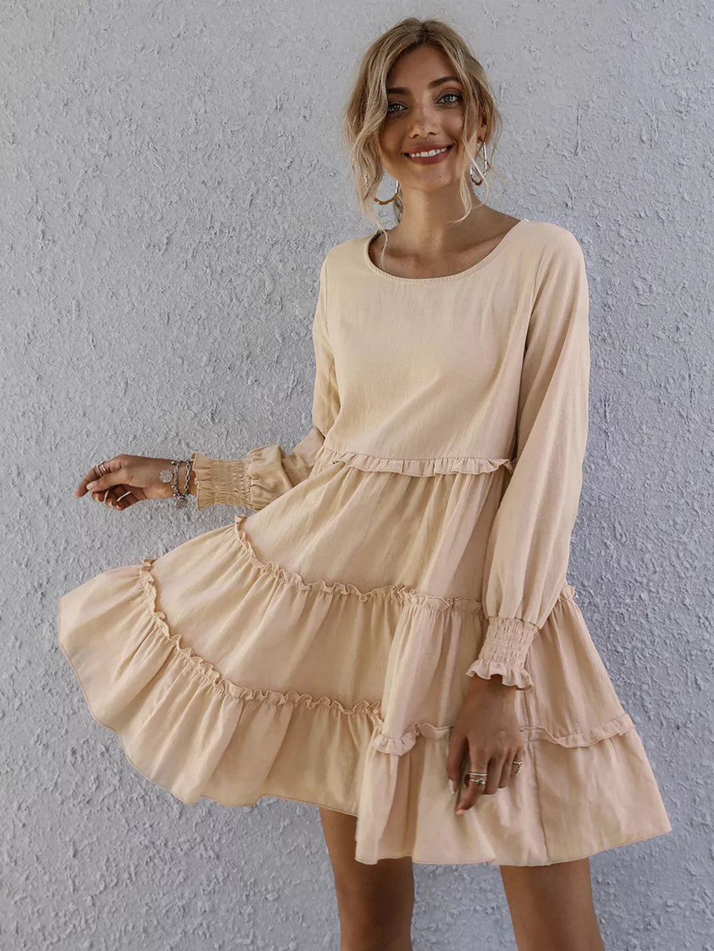 Apricot ruffled mini dress with long sleeves and tiered skirt.