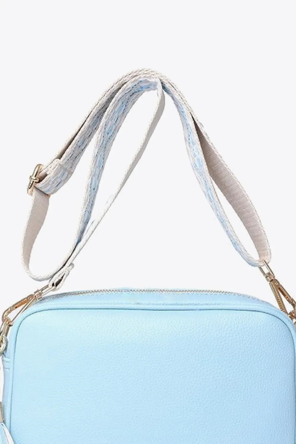 Sky blue textured crossbody bag with woven strap and gold hardware detail.
