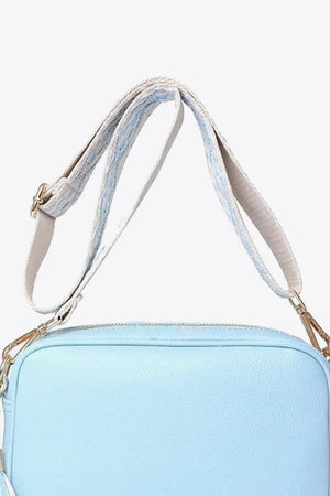 Sky blue textured crossbody bag with woven strap and gold hardware detail.