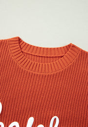 Orange knit sweater with white text detail and crew neck.