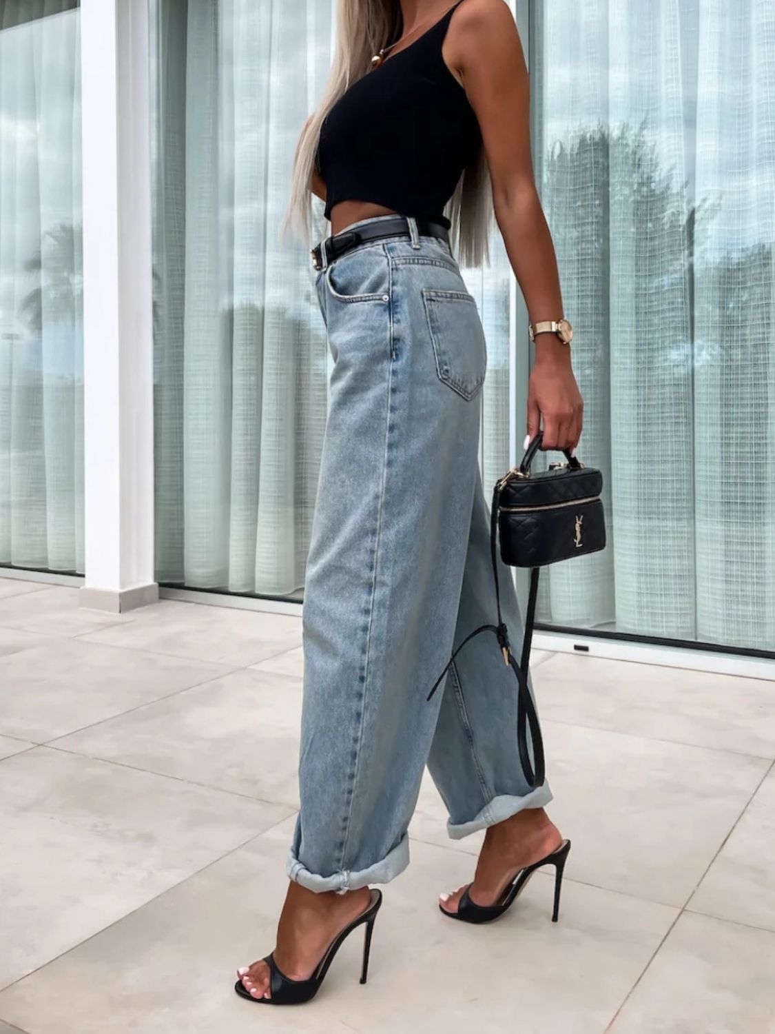 Baggy light wash denim barrel leg jeans with cuffed hems, styled with a black top and heels.