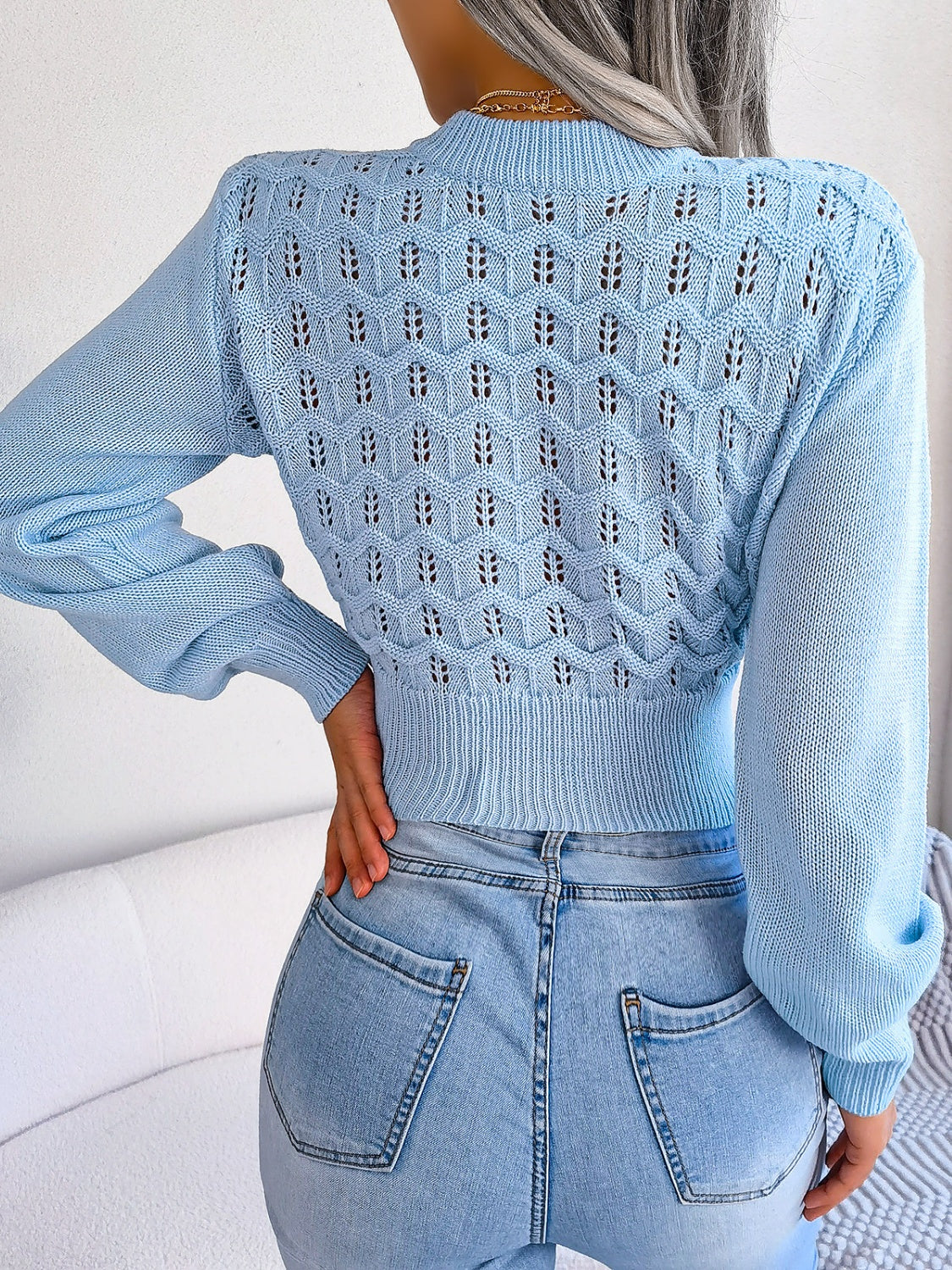 Pastel blue openwork knit sweater with puff sleeves and a textured pattern.