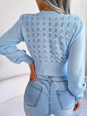 Pastel blue openwork knit sweater with puff sleeves and a textured pattern.