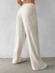 Cream wide-leg pants with buttoned pockets and a textured linen blend.