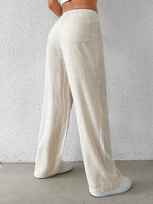 Cream wide-leg pants with buttoned pockets and a textured linen blend.