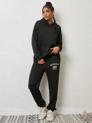 Black graphic hoodie and jogger set with "ENTHUSIASTIC 1987 REMAIN" print on pants.