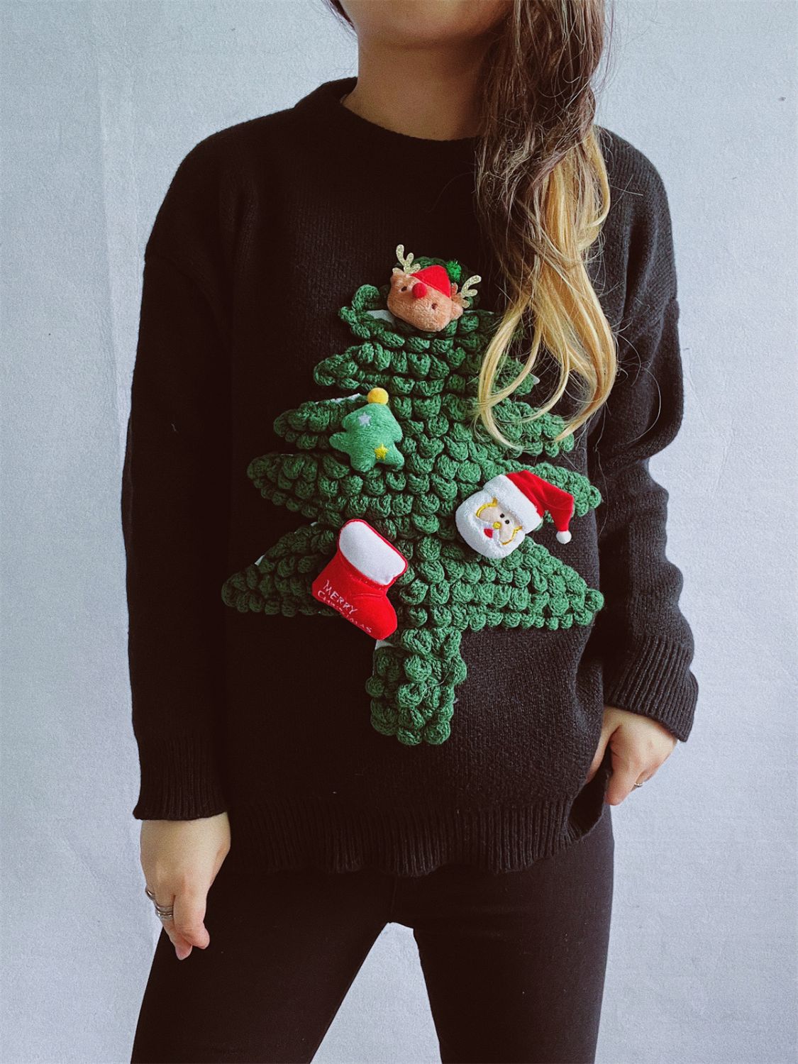 Black acrylic knit sweater with a 3D Christmas tree embellishment featuring Santa, elf, and stocking details.