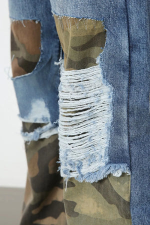 Camouflage patchwork distressed jeans in medium wash denim with frayed rips and camo print panels.