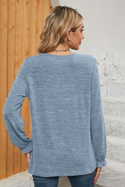 Light blue knit top with ruffled cuffs and long sleeves.