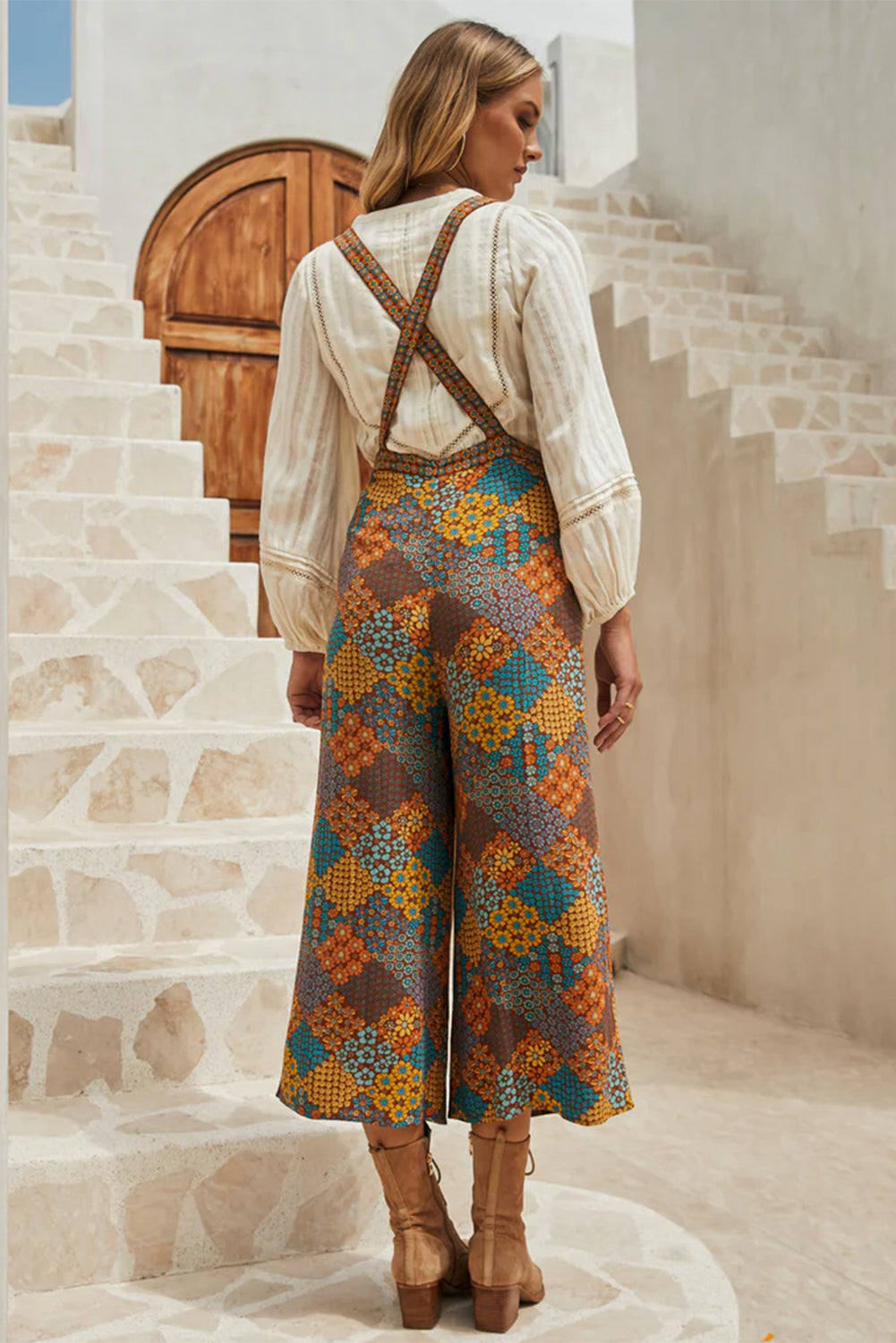 Floral patchwork culotte jumpsuit with criss-cross straps and wide legs.