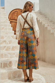 Floral patchwork culotte jumpsuit with criss-cross straps and wide legs.