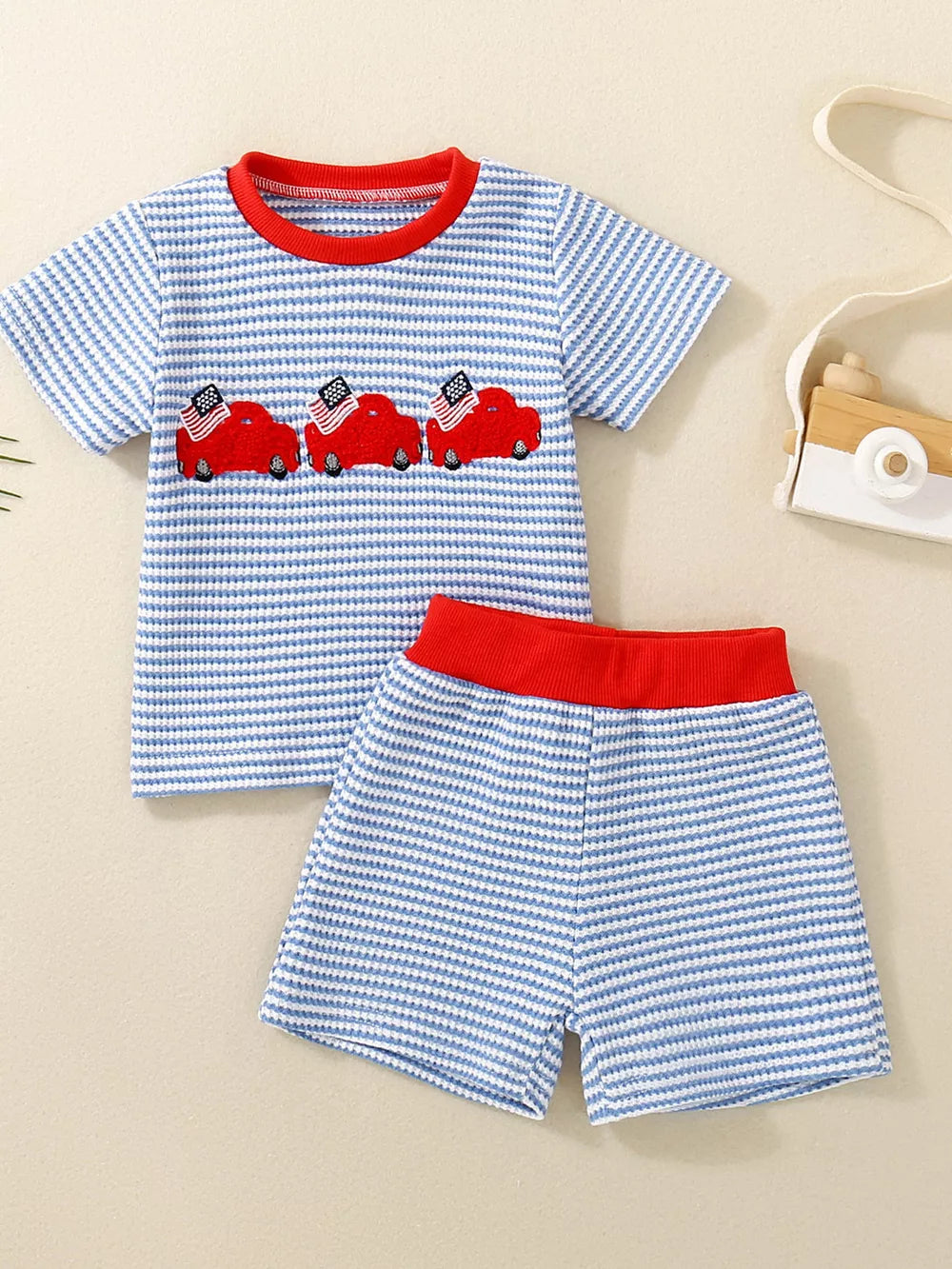 Baby boys' blue striped tee and shorts set with red car embroidery and red trim.