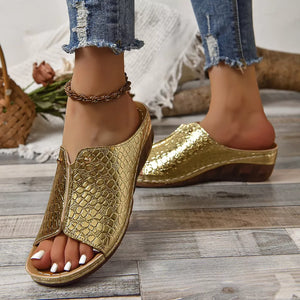 Gold glossy crocodile-embossed wedge sandals with open toe and wedge heel.