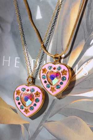 Gold locket heart pendant necklace with iridescent gem, stars, and blue gems