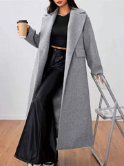 Gray wool-blend longline overcoat with notch lapels and flap pockets, worn open over black pants.