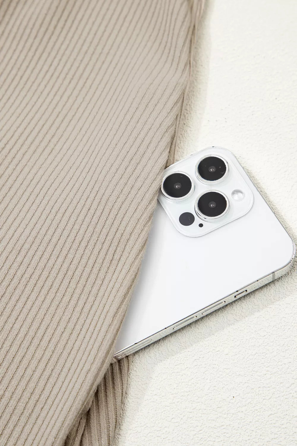 Beige ribbed knit mini dress detail with a white smartphone.