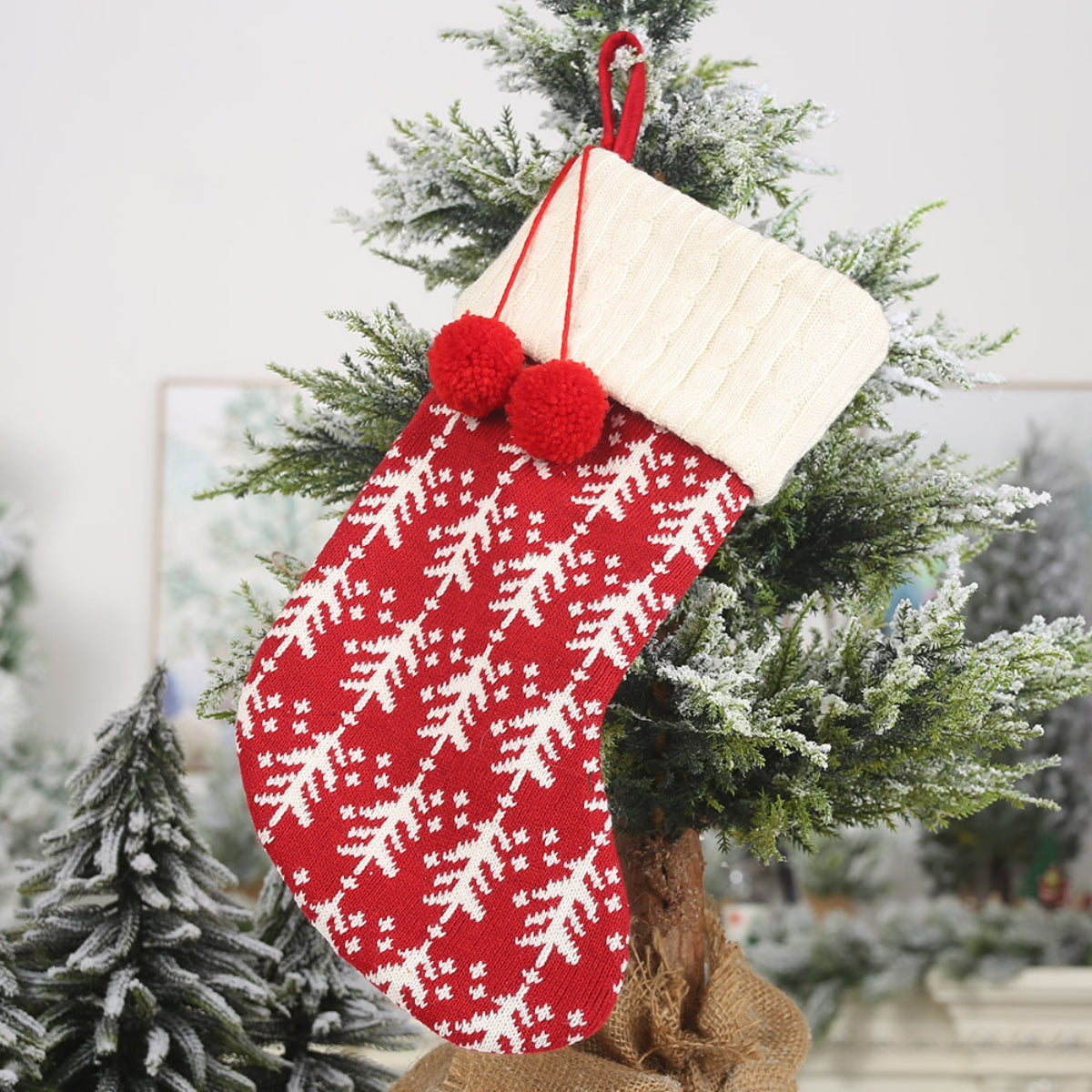 Red knit Christmas stocking with white tree pattern, cream cuff, and red pom-poms.