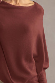 Burgundy off-shoulder knit sweater with textured cuffs and draped sleeves.