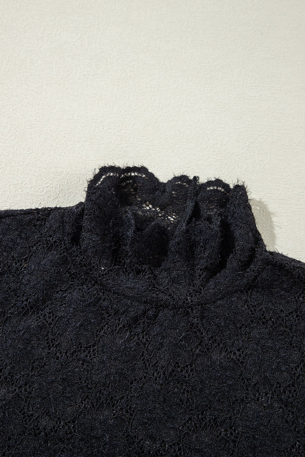Black floral lace turtleneck blouse with ruffled neckline detail.