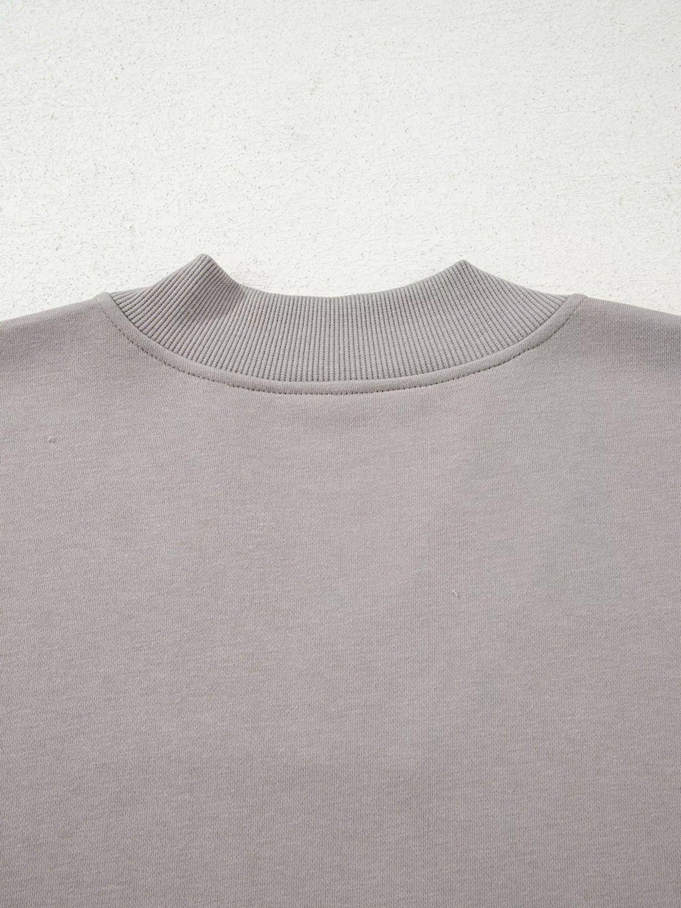 Gray sweatshirt with ribbed mock neck detail and embroidered Aztec pattern.