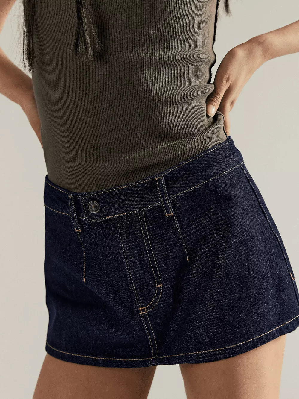 Dark blue denim mini skort with button closure and contrast stitching.