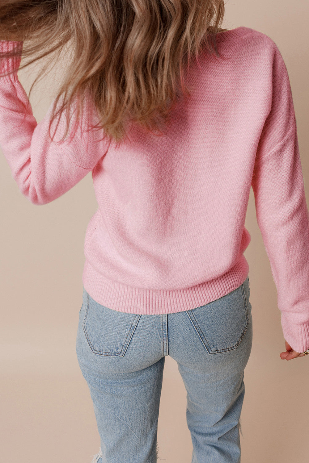 Blush pink knit sweater with floral appliqué detail and ribbed cuffs and hem.