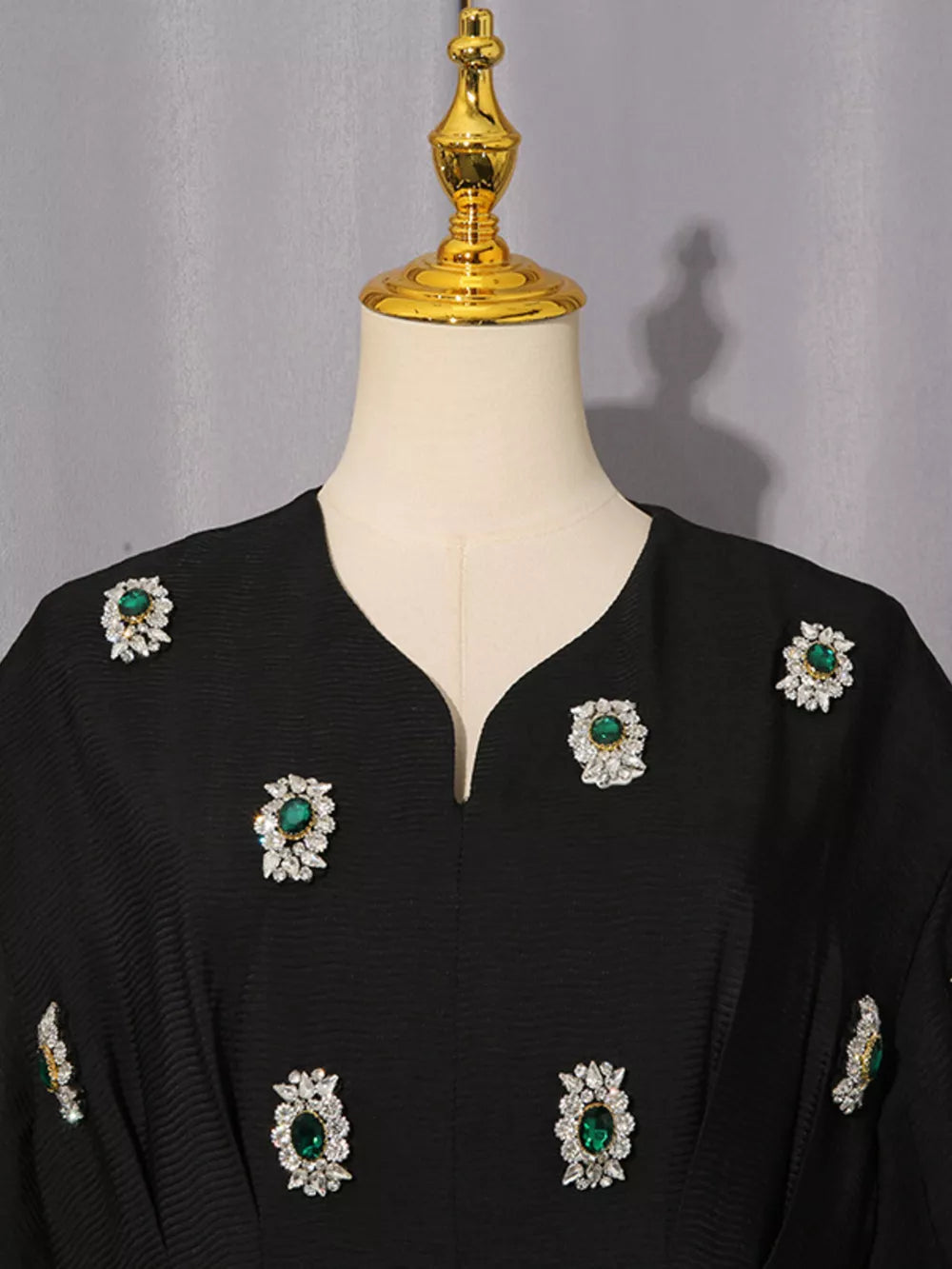 Black midi dress with puff sleeves and scattered rhinestone and emerald embellishments.