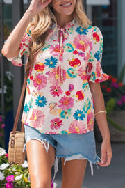Vibrant floral print shirt with tie neck, ruffled collar, and ruched short sleeves.