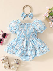 Sky blue baby dress with bunny print, smocked bodice, puff sleeves, ruffled hem, and matching headband.