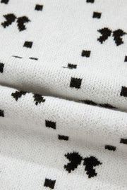 White knit sweater with a black diamond bow pattern